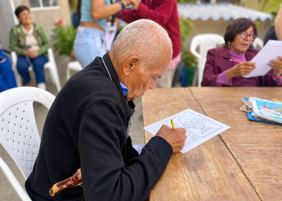Adulto mayor colorea un dibujo durante un taller al aire libre