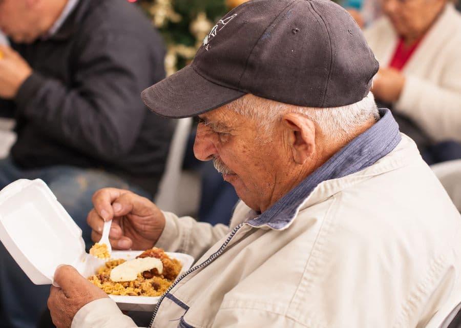 Adulto mayor disfruta un almuerzo durante una jornada de la fundación