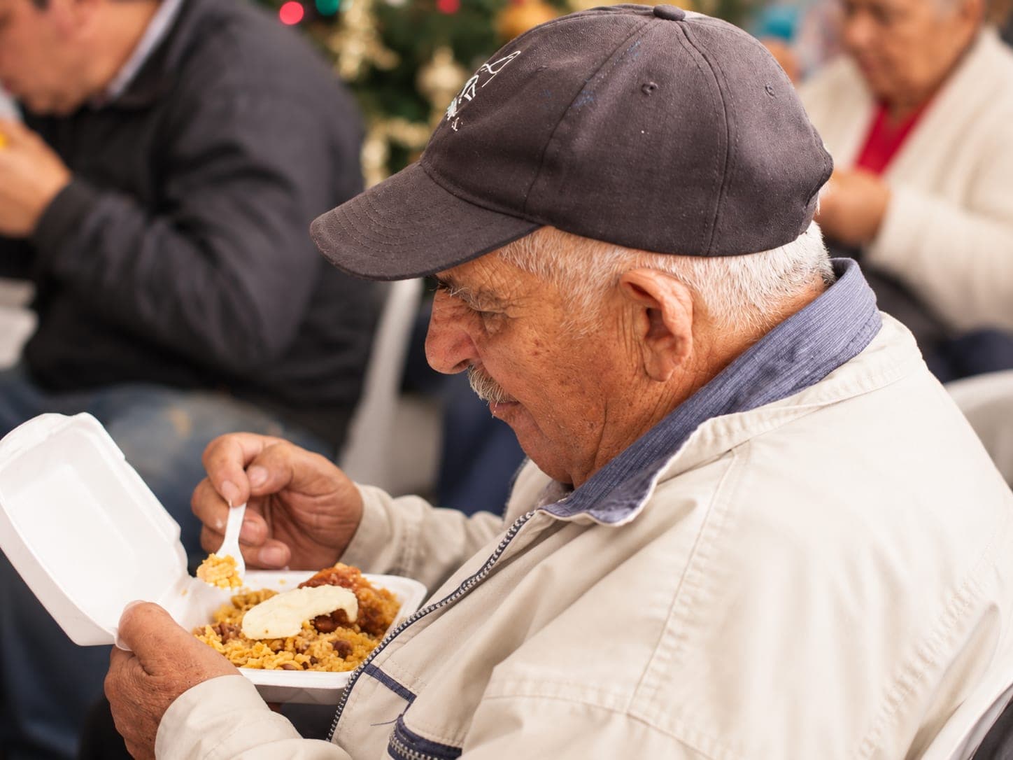 Adulto mayor disfruta un almuerzo durante una jornada de la fundación