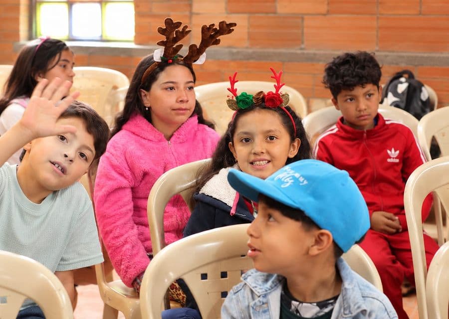 Niñas y niños sentados durante una actividad en el salón comunal